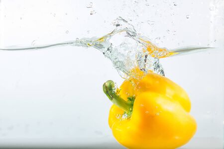 Sweet pepper in the water splashes, the yellow Sweet pepper on a white background. Sweet peppers are a type of pepper. Not spicyの写真素材