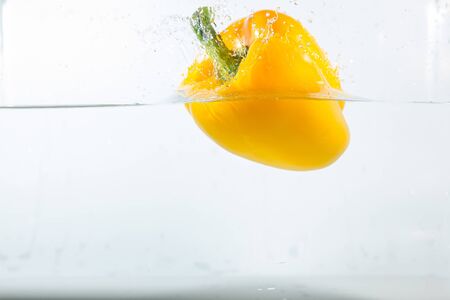 Sweet pepper in the water splashes, the yellow Sweet pepper on a white background. Sweet peppers are a type of pepper. Not spicyの写真素材