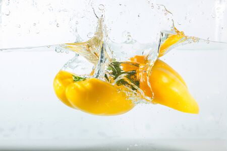 Sweet pepper in the water splashes, the yellow Sweet pepper on a white background. Sweet peppers are a type of pepper. Not spicyの写真素材