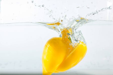 Sweet pepper in the water splashes, the yellow Sweet pepper on a white background. Sweet peppers are a type of pepper. Not spicyの写真素材