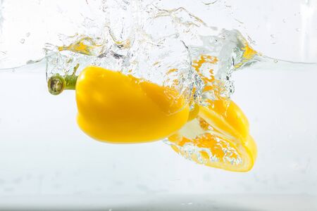 Sweet pepper in the water splashes, the yellow Sweet pepper on a white background. Sweet peppers are a type of pepper. Not spicyの写真素材