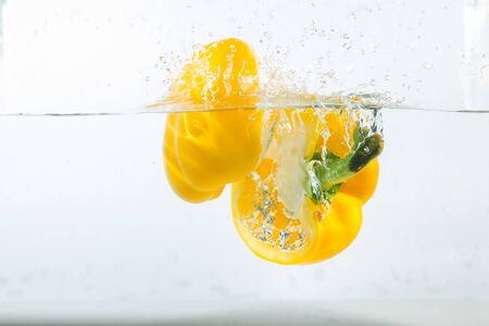 Sweet pepper in the water splashes, the yellow Sweet pepper on a white background. Sweet peppers are a type of pepper. Not spicyの写真素材