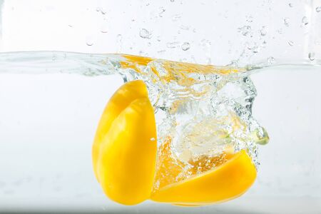 Sweet pepper in the water splashes, the yellow Sweet pepper on a white background. Sweet peppers are a type of pepper. Not spicyの写真素材