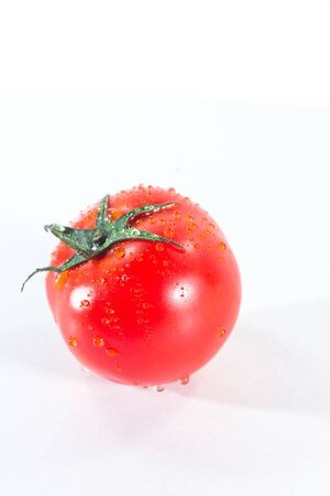 Water drops on tomatoes On a white background, when ripe tomatoes are red or orange, Tomatoes for cooking and eating fresh fruitの写真素材