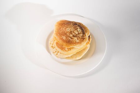 pancakes are stacked on a white plate. On a white backgroundの写真素材