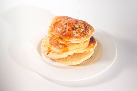 pancakes stacked on a white plate , The pancakes are topped with honeyの写真素材
