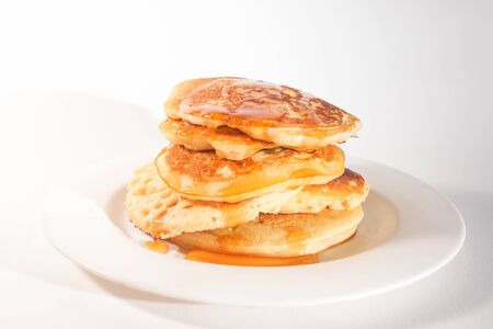 pancakes stacked on a white plate , The pancakes are topped with honeyの写真素材