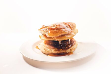 pancakes stacked on a white plate , The pancakes are topped with honeyの写真素材