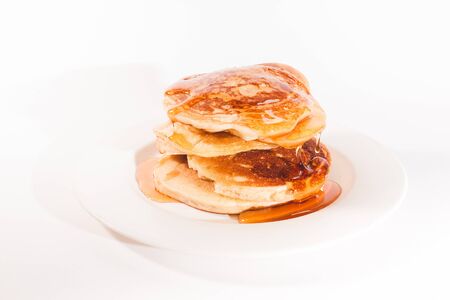 pancakes stacked on a white plate , The pancakes are topped with honeyの写真素材