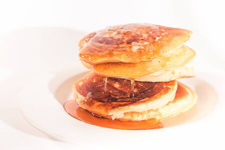 pancakes stacked on a white plate , The pancakes are topped with honeyの写真素材