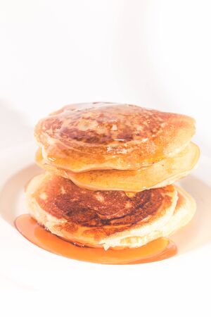 pancakes stacked on a white plate , The pancakes are topped with honeyの写真素材