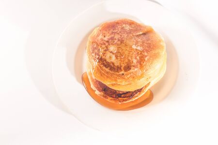pancakes stacked on a white plate , The pancakes are topped with honeyの写真素材