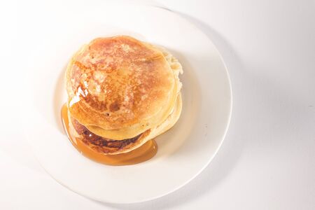 pancakes stacked on a white plate , The pancakes are topped with honeyの写真素材