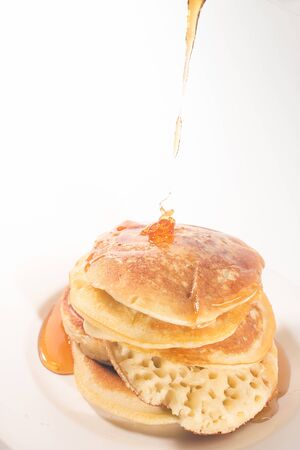 pancakes stacked on a white plate , The pancakes are topped with honeyの写真素材