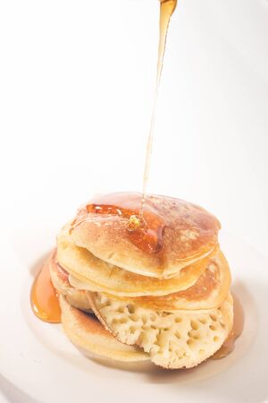pancakes stacked on a white plate , The pancakes are topped with honeyの写真素材