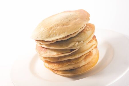 pancakes are stacked on a white plate. On a white backgroundの写真素材