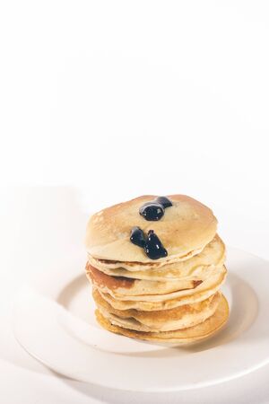 pancakes, stacked on a white plate, are topped with chocolate.の写真素材