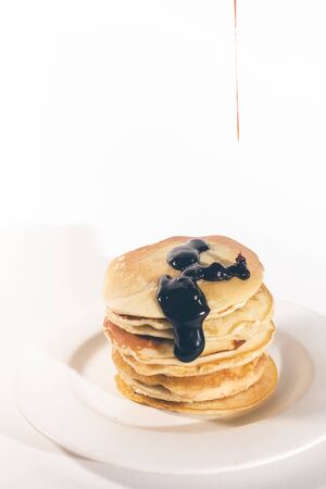 pancakes, stacked on a white plate, are topped with chocolate.の写真素材