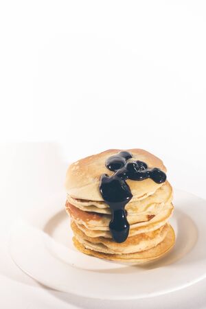 pancakes, stacked on a white plate, are topped with chocolate.の写真素材