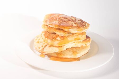pancakes stacked on a white plate , The pancakes are topped with honeyの写真素材