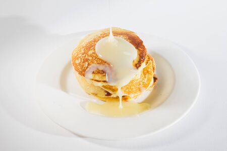 pancakes stacked on a white plate,
Pancakes are topped with sweetened condensed milk.の写真素材