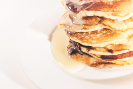 pancakes stacked on a white plate,Pancakes are topped with sweetened condensed milk.