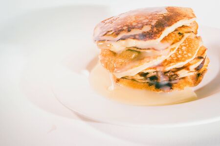 pancakes stacked on a white plate,
Pancakes are topped with sweetened condensed milk.の写真素材