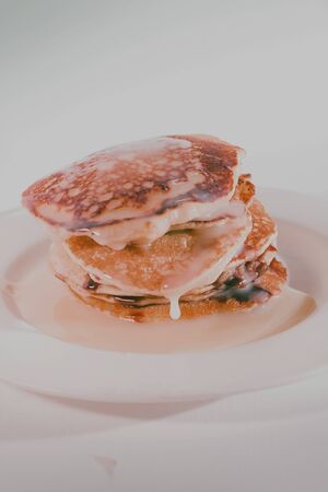 pancakes stacked on a white plate,
Pancakes are topped with sweetened condensed milk.の写真素材