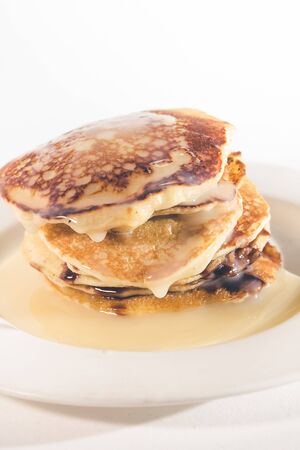 pancakes stacked on a white plate,
Pancakes are topped with sweetened condensed milk.の写真素材