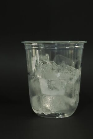 Ice cubes in plastic glasses on a black backgroundの写真素材