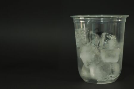 Ice cubes in plastic glasses on a black backgroundの写真素材