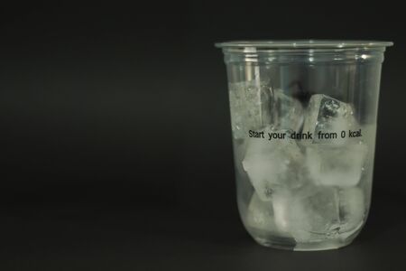 Ice cubes in plastic glasses on a black backgroundの写真素材