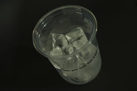 Ice cubes in plastic glasses on a black backgroundの写真素材