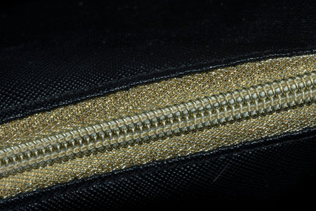 Golden zipped on a black background , Golden plastic zipper