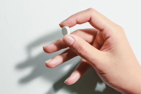Medication on hand,
White seed medicine on fingers, on a blue backgroundの写真素材