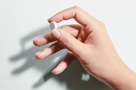 Medication on hand,
White seed medicine on fingers, on a blue backgroundの写真素材