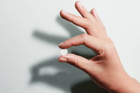 Medication on hand,
White seed medicine on fingers, on a blue backgroundの写真素材