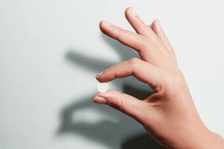 Medication on hand,
White seed medicine on fingers, on a blue backgroundの写真素材