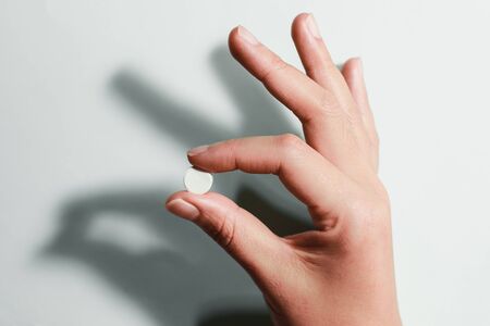 Medication on hand,
White seed medicine on fingers, on a blue backgroundの写真素材
