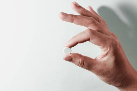 Medication on hand,
White seed medicine on fingers, on a blue backgroundの写真素材