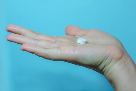 Medication on hand,
White seed medicine on the palm, on a blue backgroundの写真素材