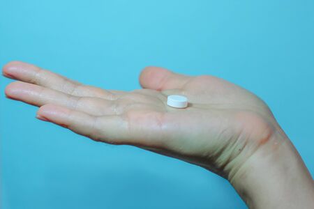 Medication on hand,
White seed medicine on the palm, on a blue backgroundの写真素材