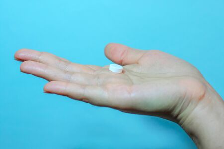 Medication on hand,
White seed medicine on the palm, on a blue backgroundの写真素材