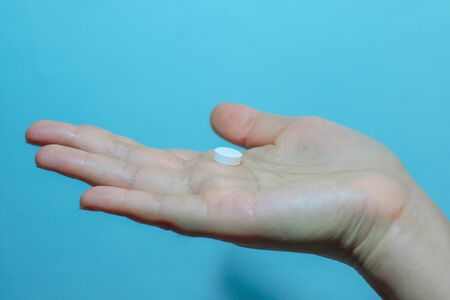 Medication on hand,
White seed medicine on the palm, on a blue backgroundの写真素材