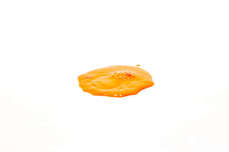 Orange water droplets splashing on a white backgroundの写真素材
