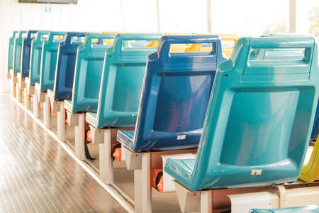 The blue plastic chair's seat on the boat is fastened to the wooden floor.の写真素材