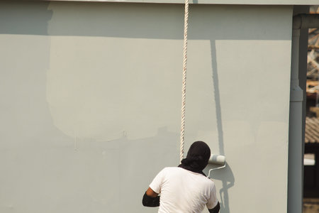 A male worker is painting a tall building abseiling.