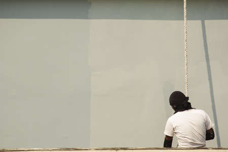 A male worker is painting a tall building abseiling.の写真素材