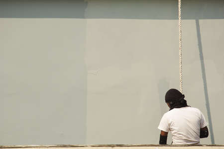 A male worker is painting a tall building abseiling.の写真素材