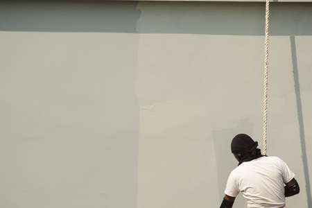 A male worker is painting a tall building abseiling.の写真素材